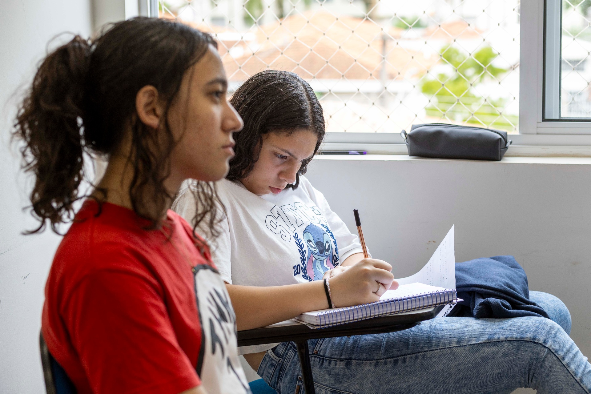 Duas alunas estudando junto à janela