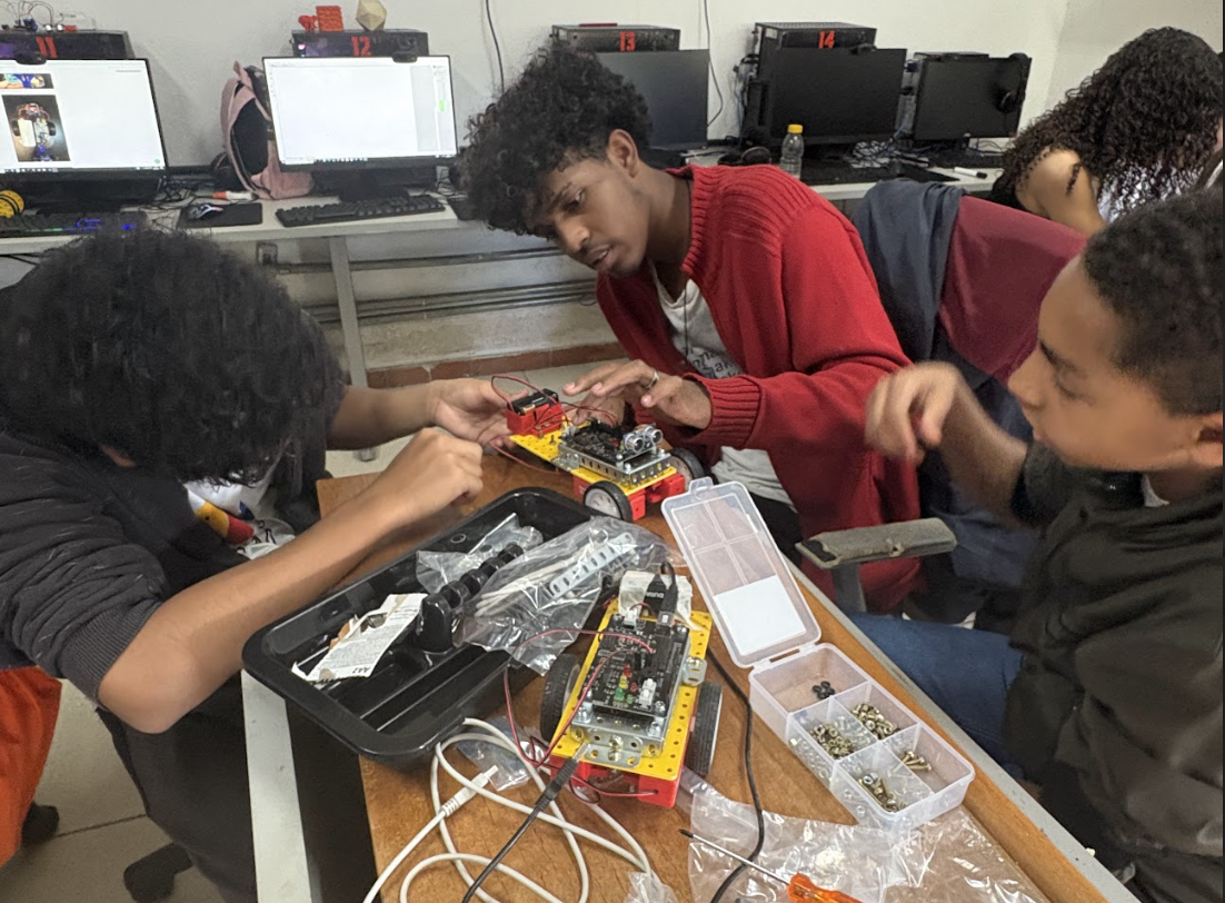 Jovens montando robô em oficina de robótica